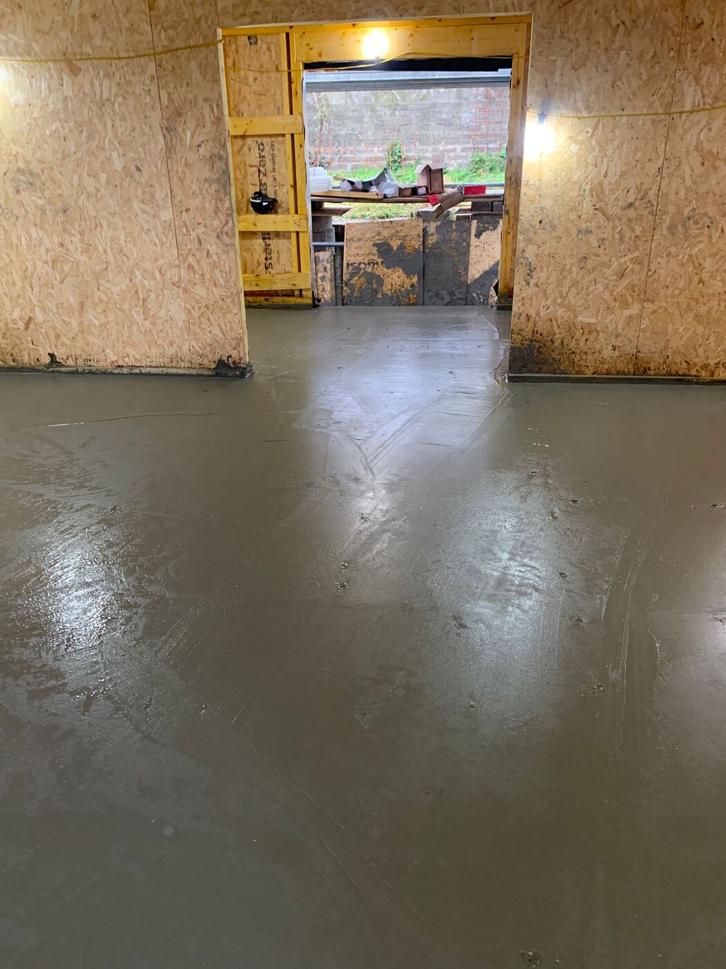 Freshly poured and levelled concrete screed floor covering the underfloor heating pipework