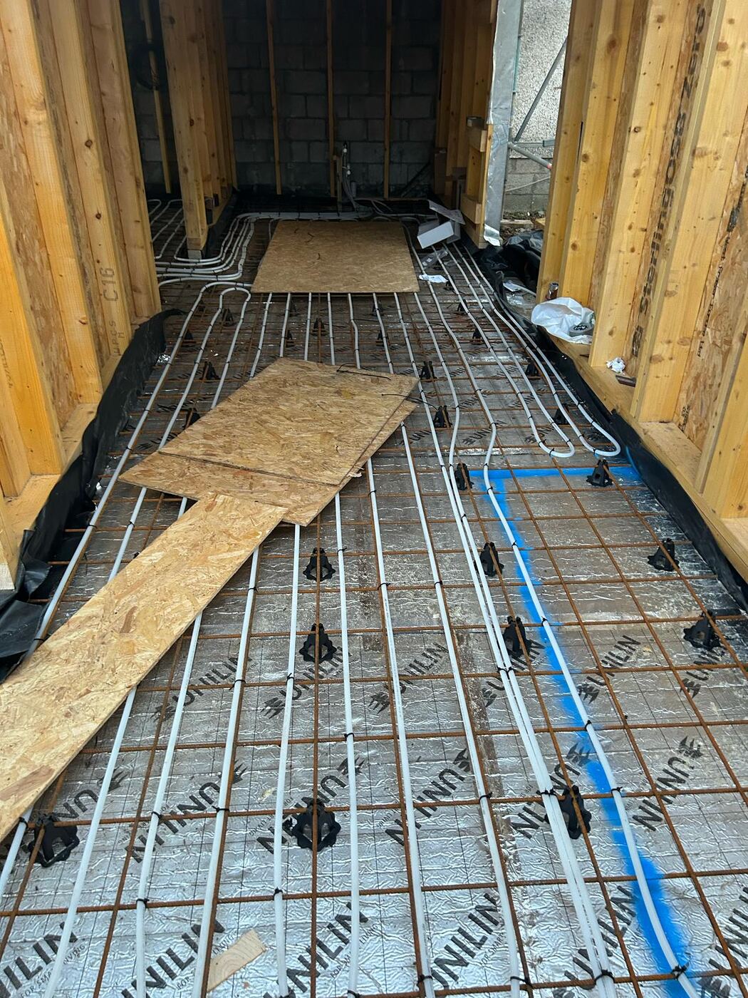 Underfloor heating pipework laid out in loops over insulation and reinforcing mesh, ready for the screed pour